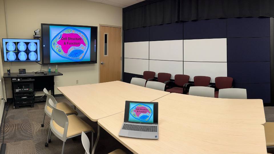 conference table with a laptop computer and a wall-mounted screen