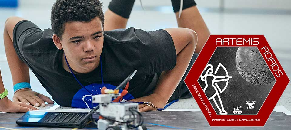Boy on the floor with a laptop, Lego robot and the Artemis Roads logo: 2022-2023 National NASA Student Challenge
