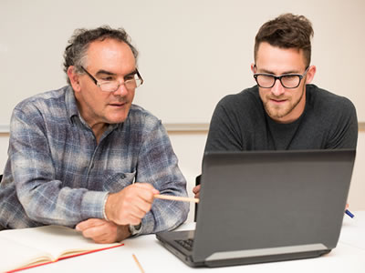 Prof and student working on a computer