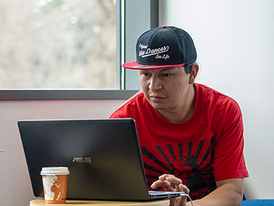 Male Native American student working on a laptop