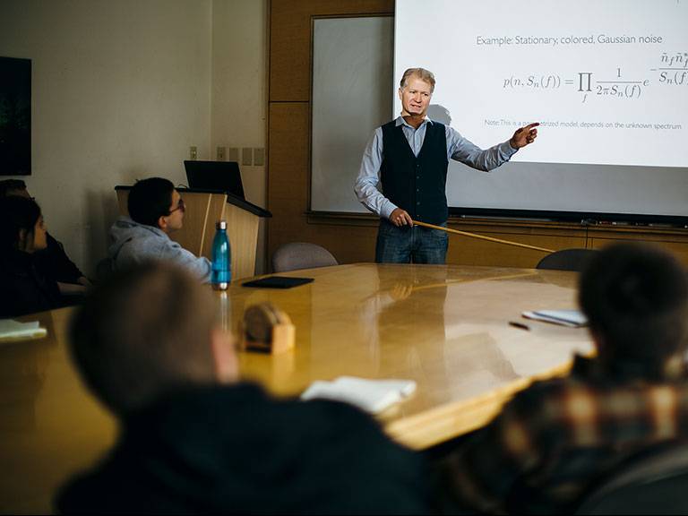 Male professor teaching in front of a group of students
